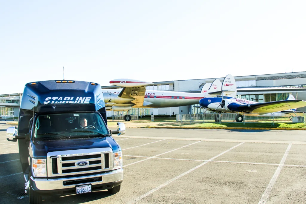 Starline Collection luxury charter bus parked outside aviation museum with vintage aircraft on display