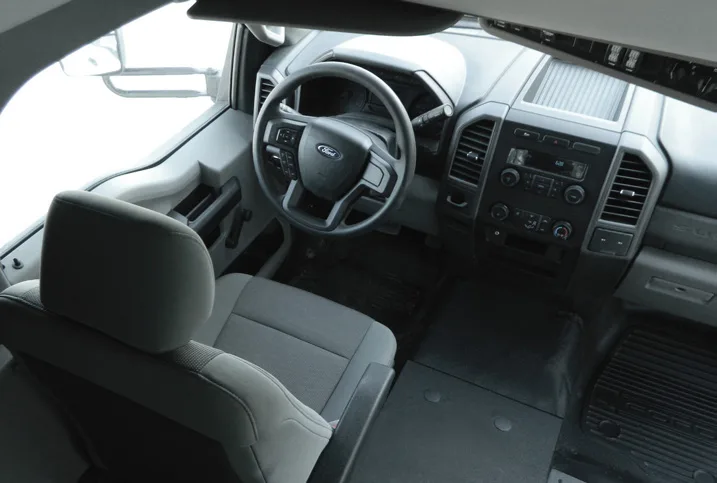 Ford vehicle interior featuring driver seat, steering wheel, and dashboard controls