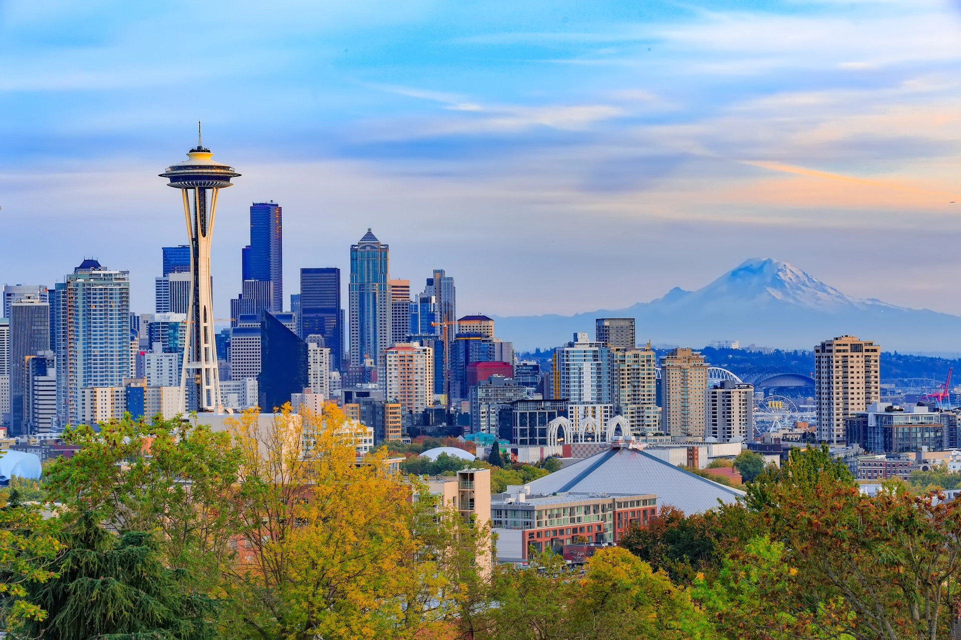 Seattle skyline featuring the Space Needle and downtown skyscrapers with Mount Rainier visible in the distance in autumn