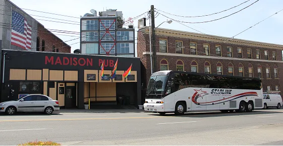 Starline Collection charter bus parked outside Madison Pub in an urban Pacific Northwest streetscape