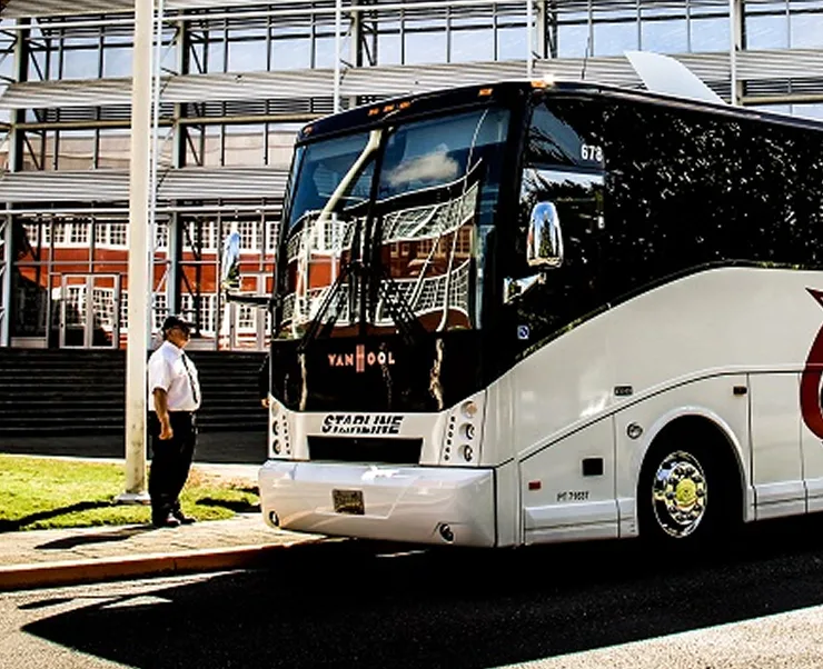 Starline Collection uniformed driver standing beside a luxury Van Hool charter coach at a professional venue