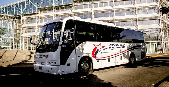Starline luxury charter bus parked outside a modern glass convention center building
