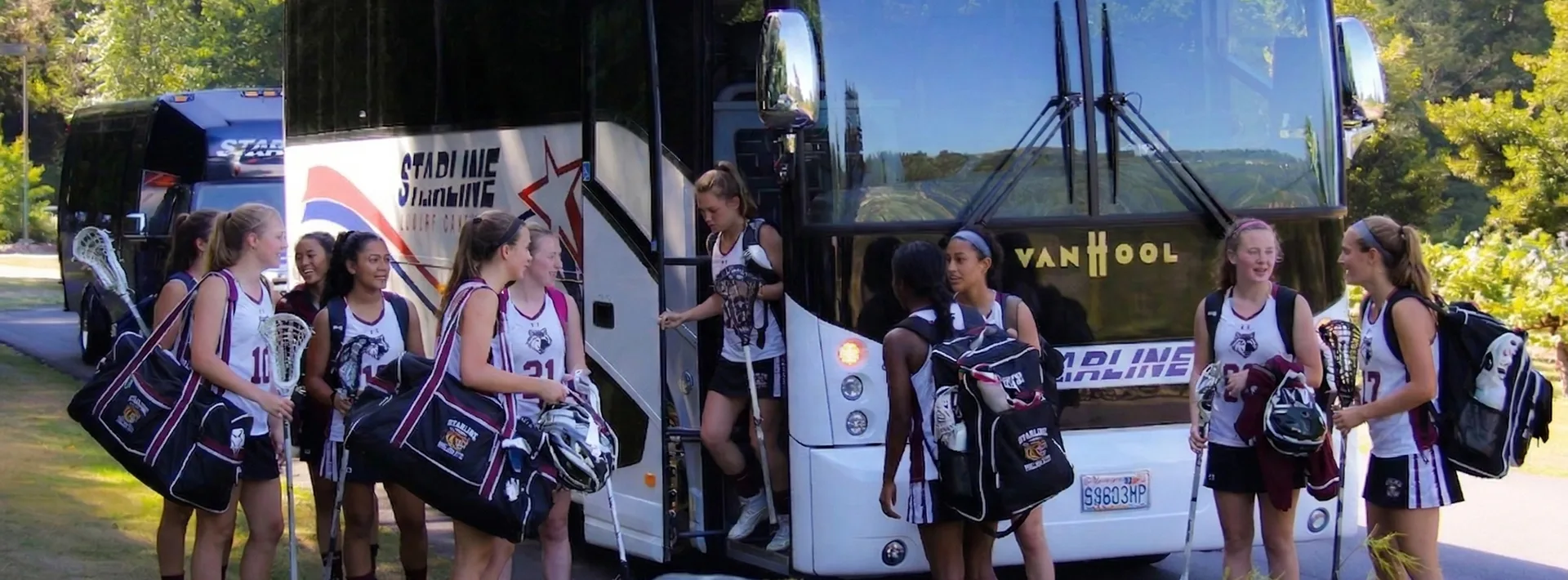 Girls lacrosse team boarding a Starline luxury charter bus with equipment and gear bags