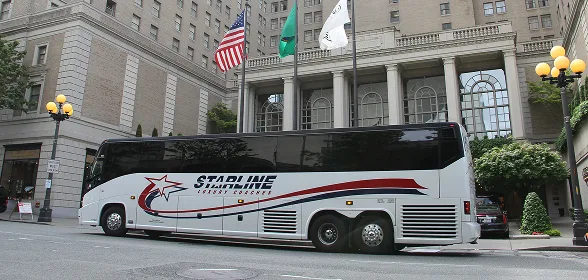 Starline luxury charter bus parked in front of an elegant historic hotel in the Pacific Northwest