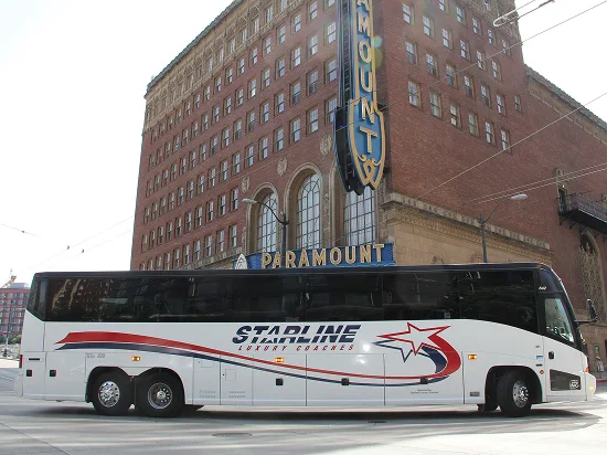 Starline Luxury Coaches charter bus parked in front of the historic Paramount Theatre building