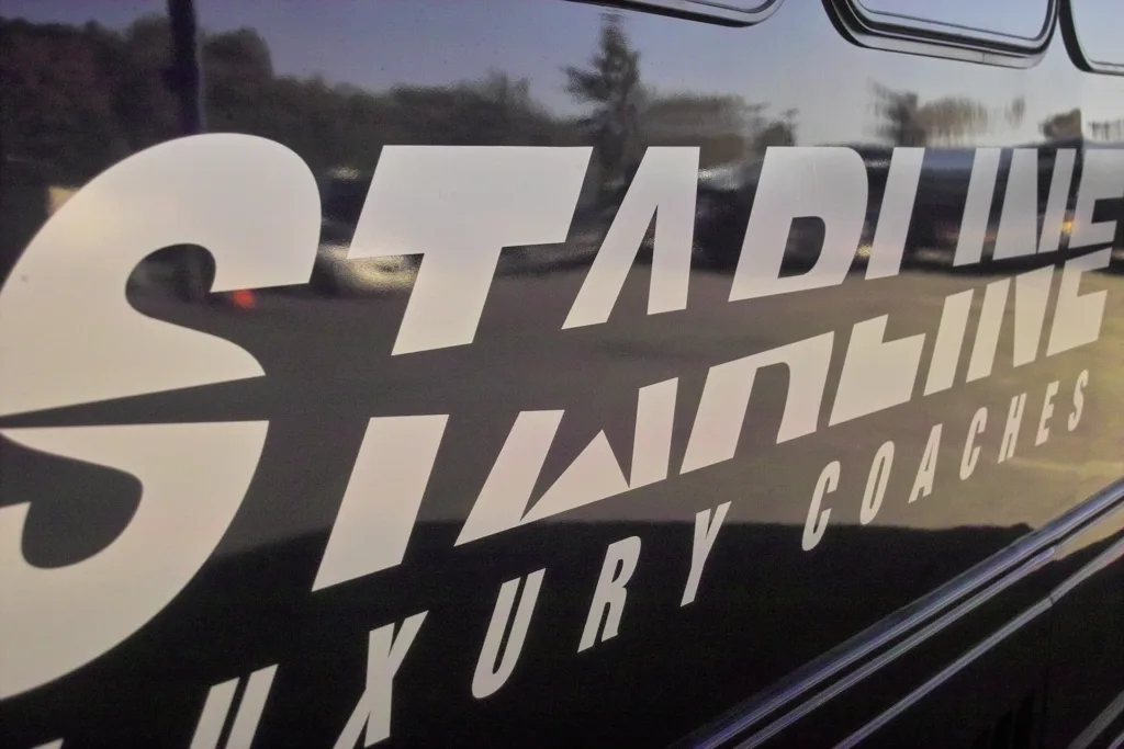 Close-up of Starline Luxury Coaches bold white logo on a polished black charter bus exterior