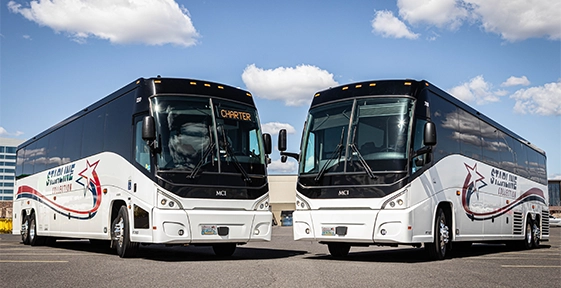 Two white Starline Collection MCI motorcoaches parked side by side with Charter sign displayed on windshield