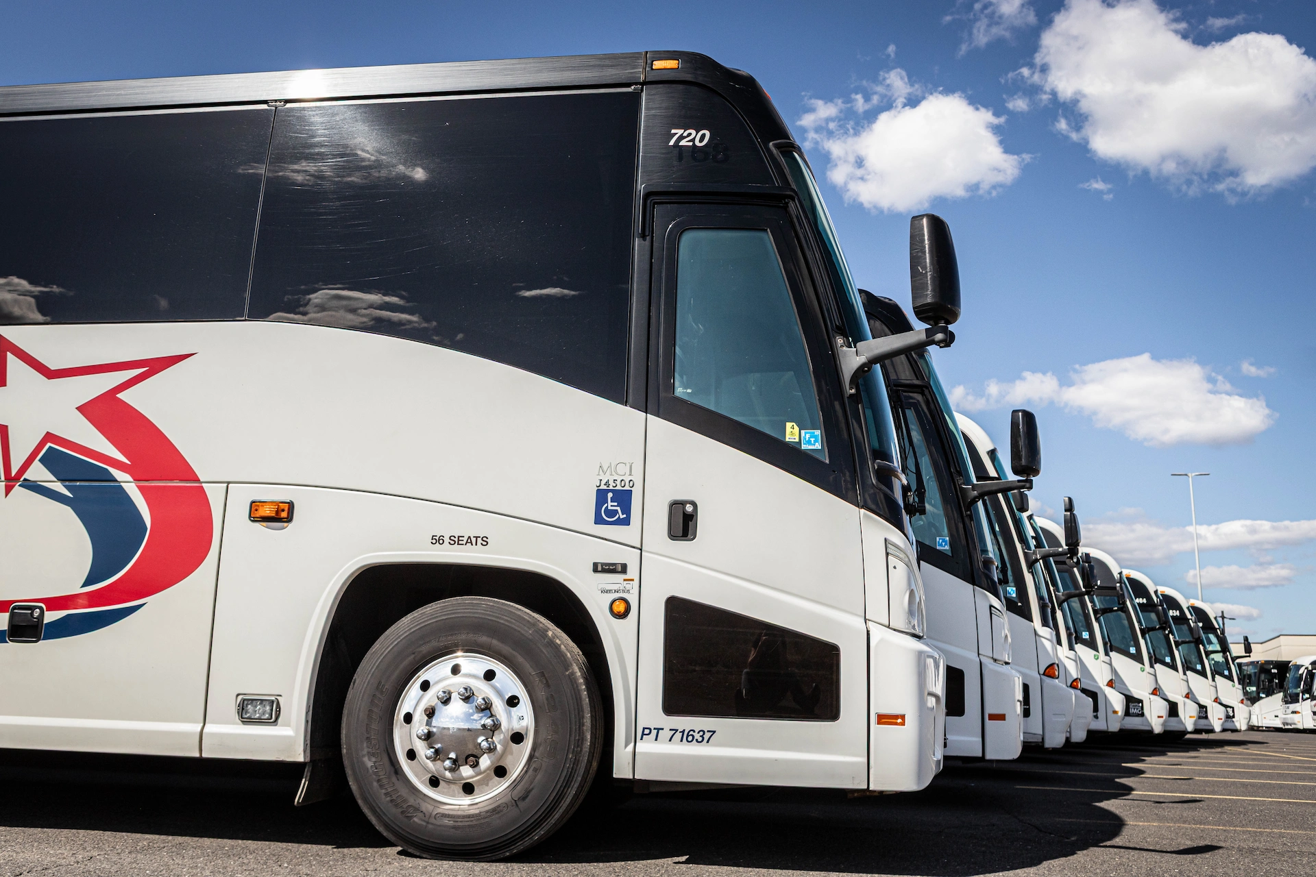 Row of Starline MCI J4500 56-seat ADA-accessible motorcoaches lined up at depot under blue sky