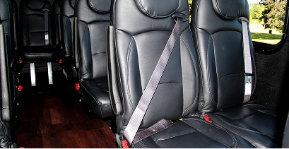 Starline mini coach interior showing black leather seats with seatbelts fastened and hardwood floor