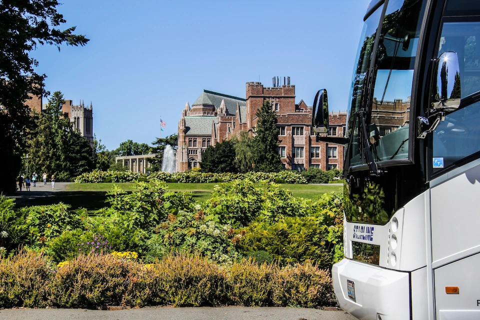 Starline motorcoach parked alongside University of Washington quad with historic brick buildings and fountain in background