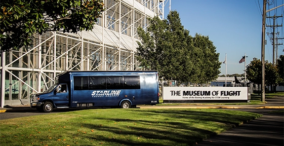 Dark blue Starline shuttle bus parked outside the Museum of Flight in Seattle on a sunny day