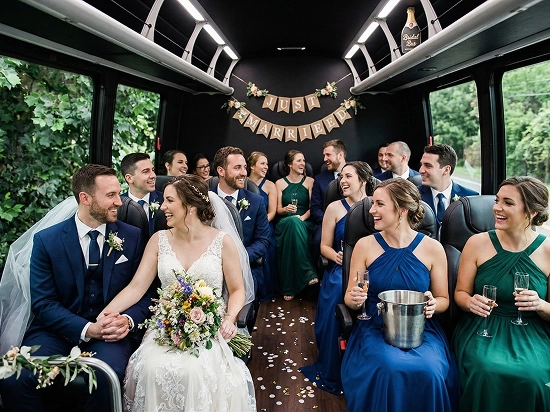 Bride, groom, and wedding party celebrating inside a Starline shuttle with a Just Married banner and champagne