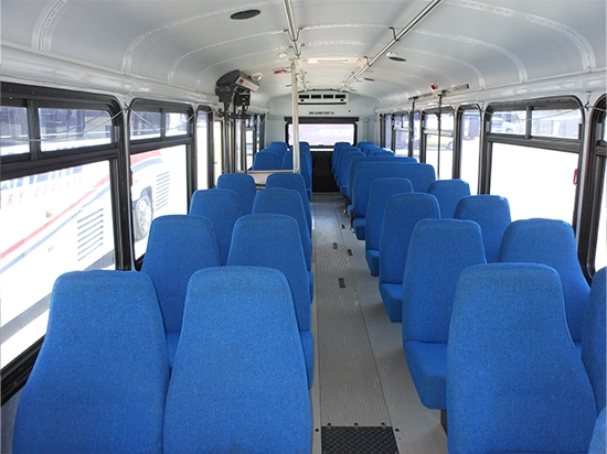 Spacious charter bus interior with rows of blue upholstered seats and wide center aisle