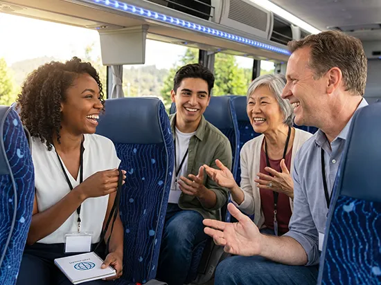 Four diverse professionals laughing and conversing in luxury charter bus blue seating