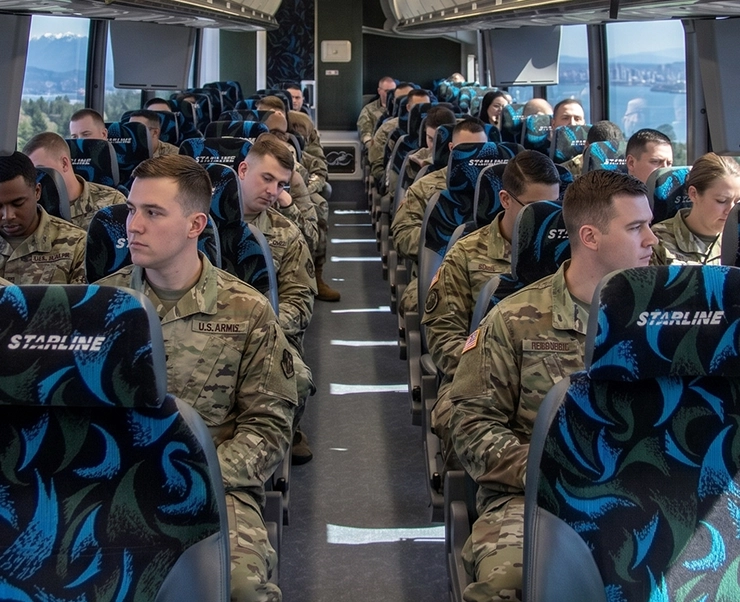 U.S. Army soldiers seated in rows aboard a Starline Collection luxury charter bus in the Pacific Northwest