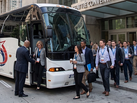 Professional attendees boarding a charter bus outside Seattle Convention Center for corporate event transportation
