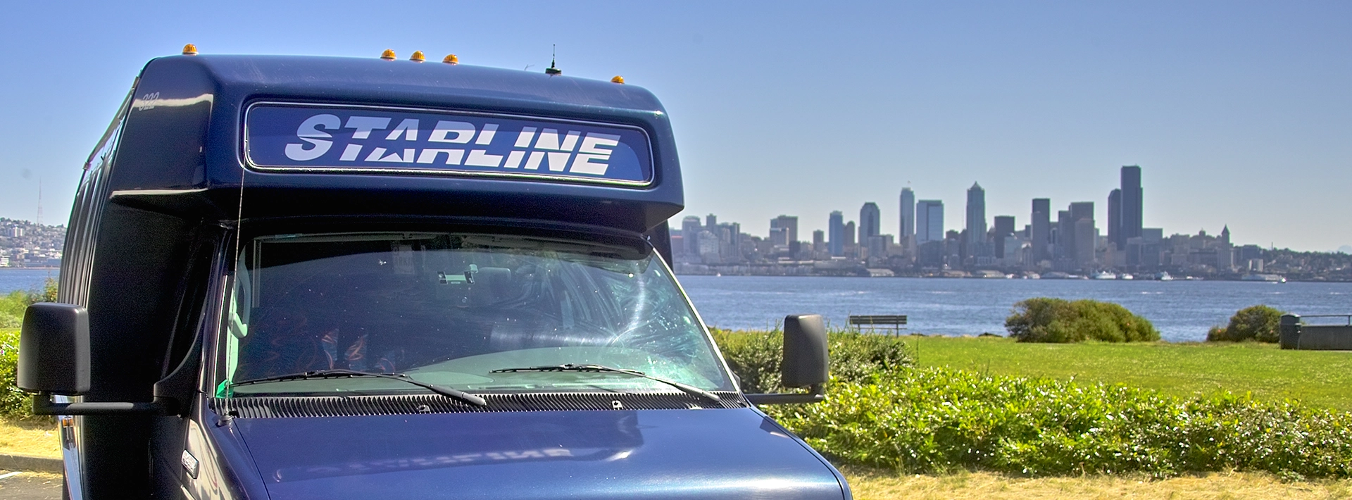 Starline luxury charter bus with Seattle skyline and Puget Sound waterfront in background