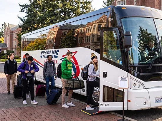 Students boarding a Starline Collection charter bus on a university campus with luggage