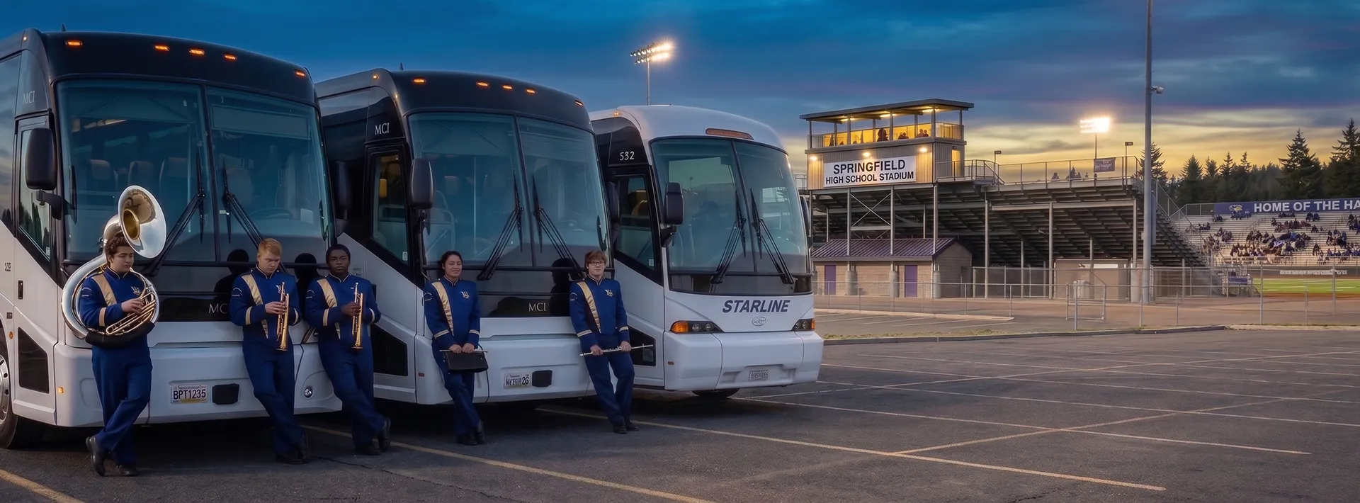 Starline charter buses parked at Springfield High School Stadium with marching band students at dusk
