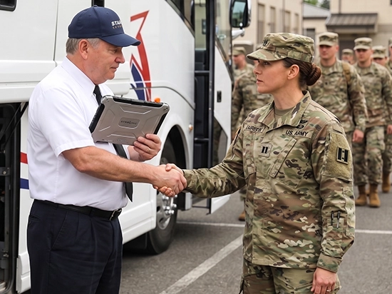 Starline driver shaking hands with US Army officer beside charter bus with soldiers in background