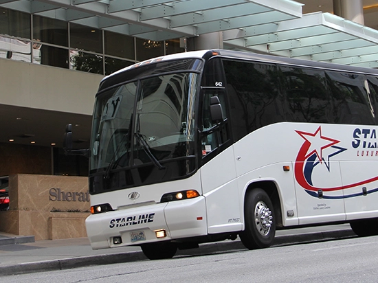 Starline luxury charter bus parked outside a Sheraton hotel in an urban setting