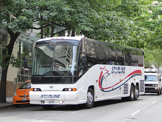 Starline Collection luxury charter bus parked on a tree-lined urban street in the Pacific Northwest