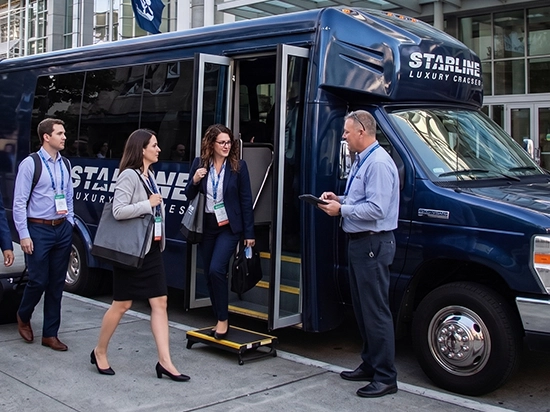 Corporate professionals boarding a Starline Luxury Charters navy blue charter bus with a professional driver