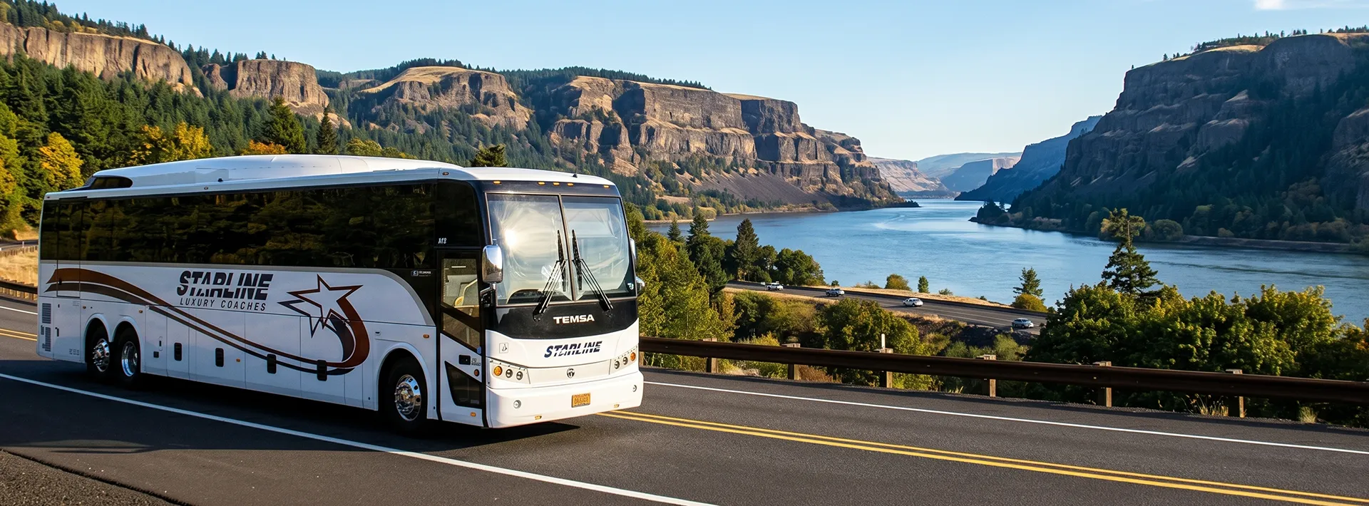 Starline Luxury Coaches charter bus traveling along a scenic Pacific Northwest highway with river and cliffs