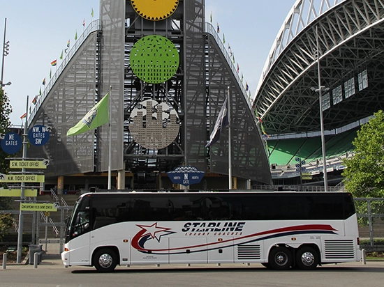 Starline Luxury Coaches charter bus parked in front of a Seattle stadium on a sunny day
