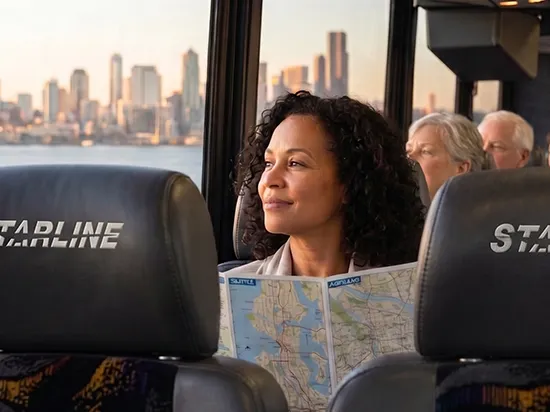 Woman reading a Seattle map aboard a Starline luxury charter bus with city skyline views at sunset