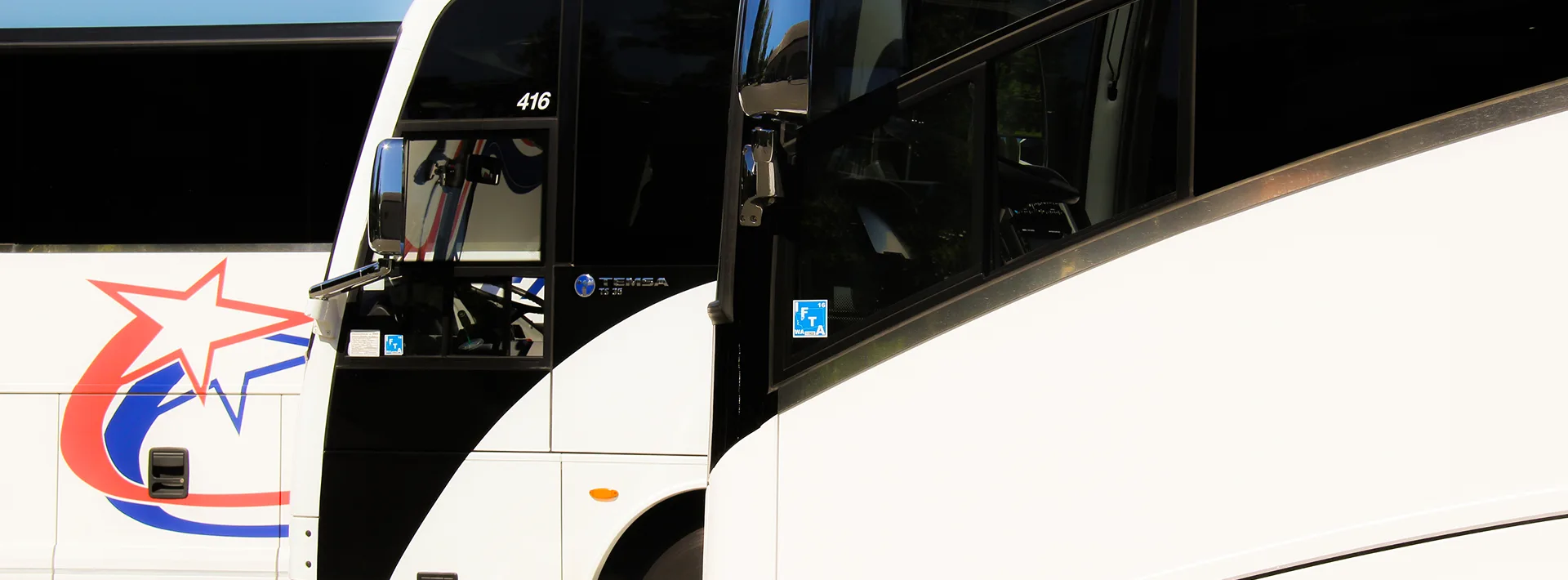 Two white Temsa motorcoaches parked side by side, one displaying a red, white, and blue star logo and numbered 416