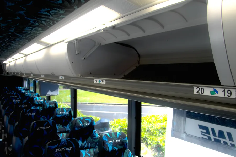 Interior of a Starline charter bus showing numbered overhead storage, overhead lighting, and rows of branded seats